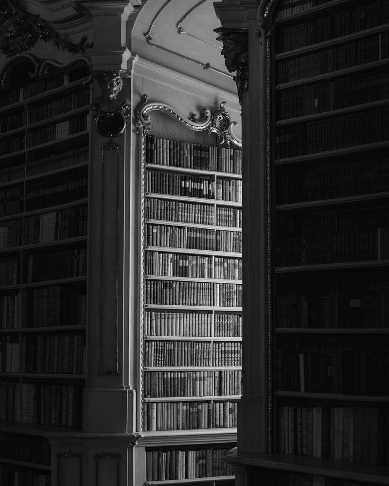 Tall library shelves lined with old leather-bound books