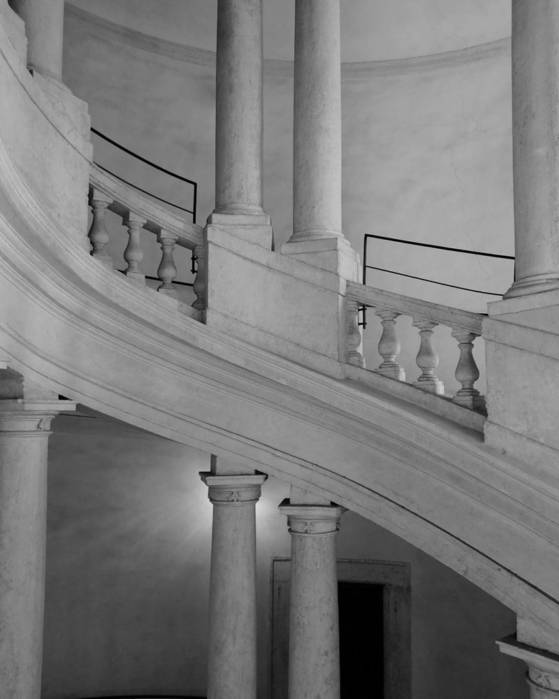 A helicoidal stone staircase curving between paired columns