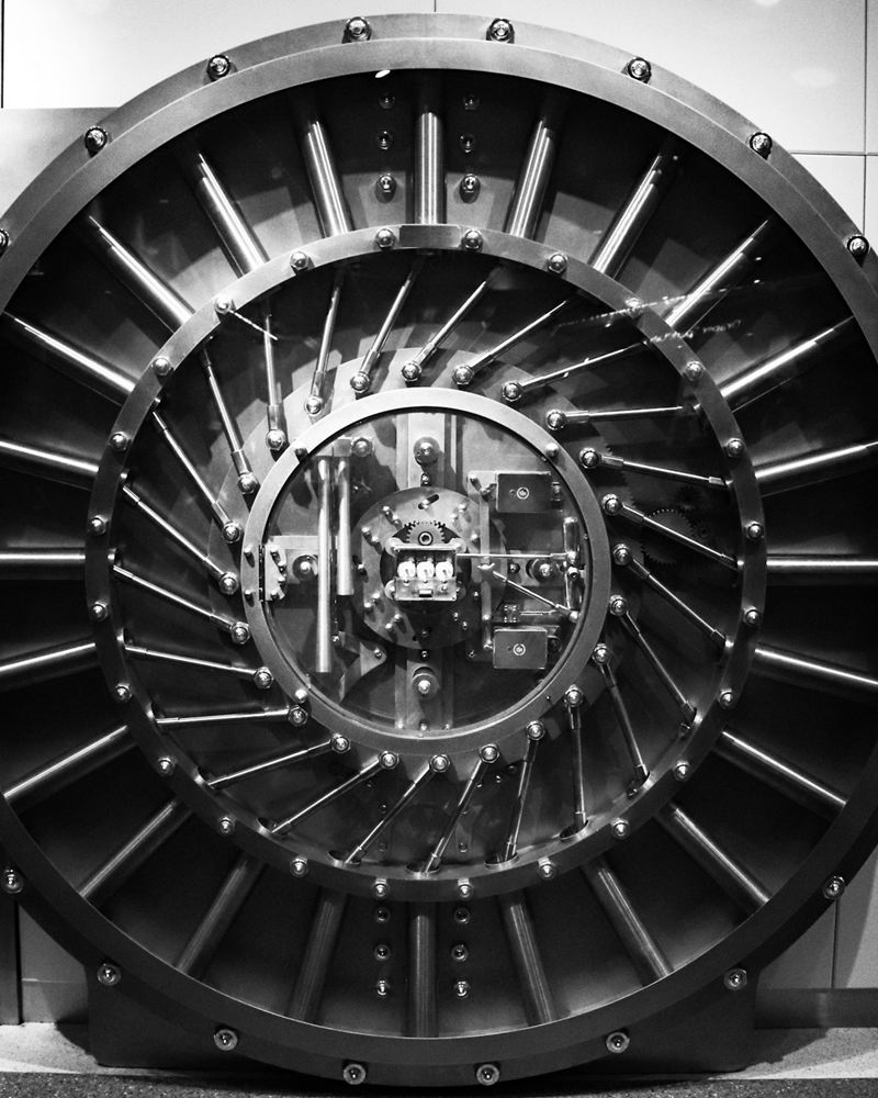 A circular steel vault door showing its radial locking bolts