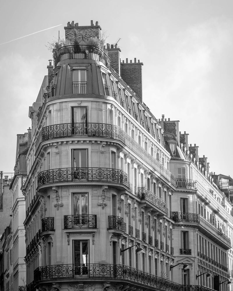 A Haussmann-era Paris apartment building with wrought-iron balconies and a mansard roof