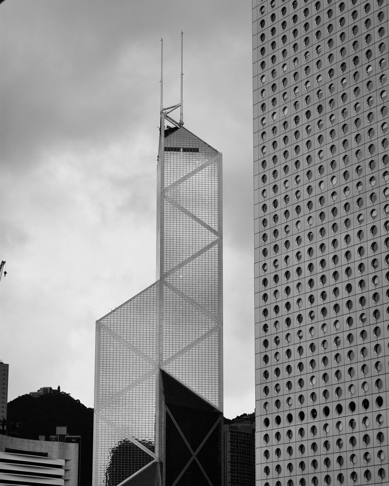 An angular glass tower beside the porthole windows of Jardine House, Central, Hong Kong