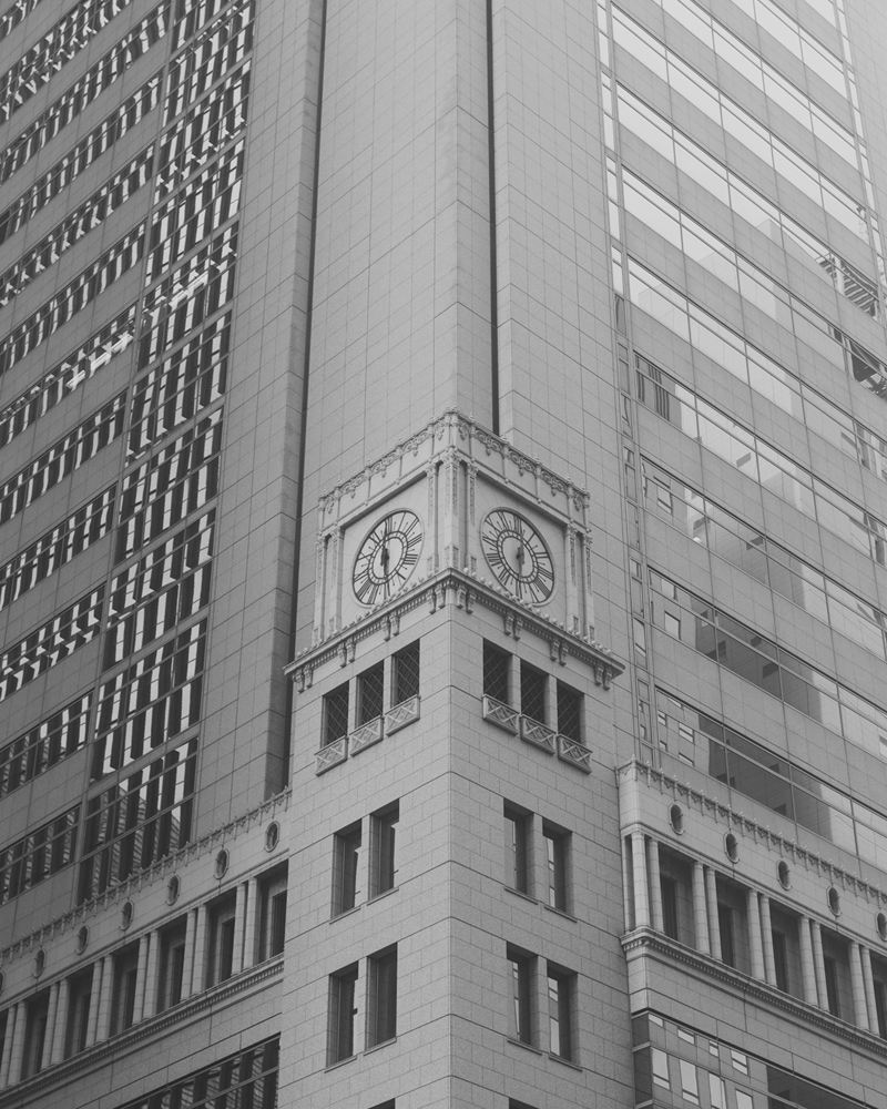 Historic clock-tower corner of a granite facade set into a modern office tower, Otemachi, Tokyo