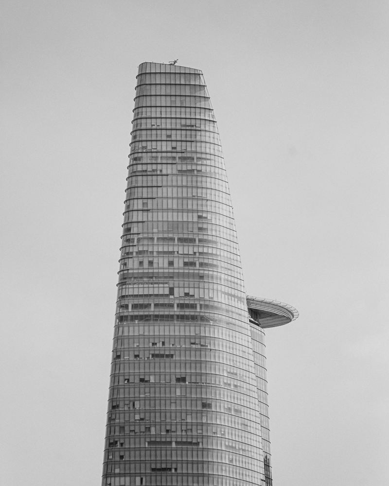 The tapering glass Bitexco Financial Tower and its helipad against a pale sky in Ho Chi Minh City