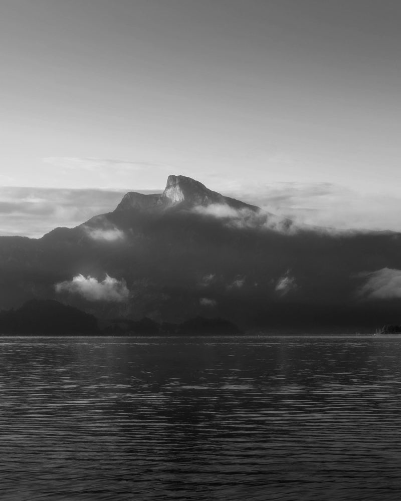 A mountain rising from still lake water at dawn