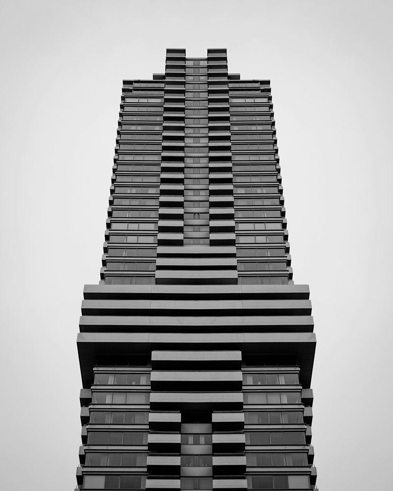 A single stepped high-rise tower rising against a plain grey sky
