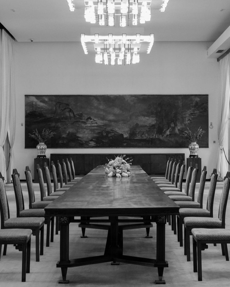 An empty formal hall with a long polished table and high-backed chairs